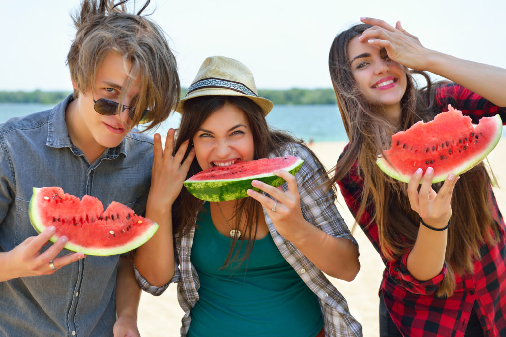 Happy friends eating watermelon on the beach. Youth lifestyle. H SUMMER SPEECH BOOSTER